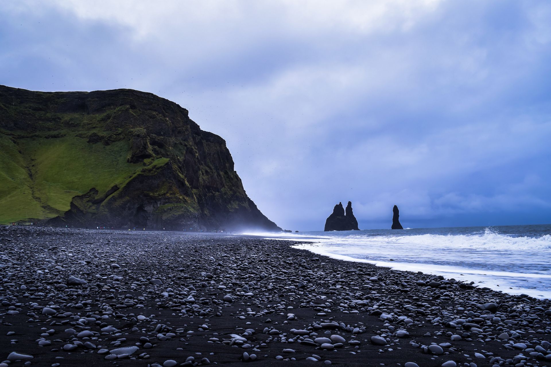A Reynisfjara fekete homokos tengerpart bazaltoszlopokkal és az Atlanti-óceán hullámaival.